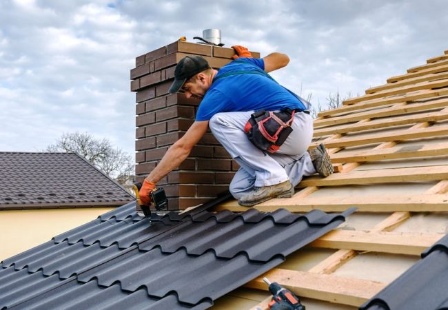 a professional master (roofer) with electric screwdriver covers repairs the roof